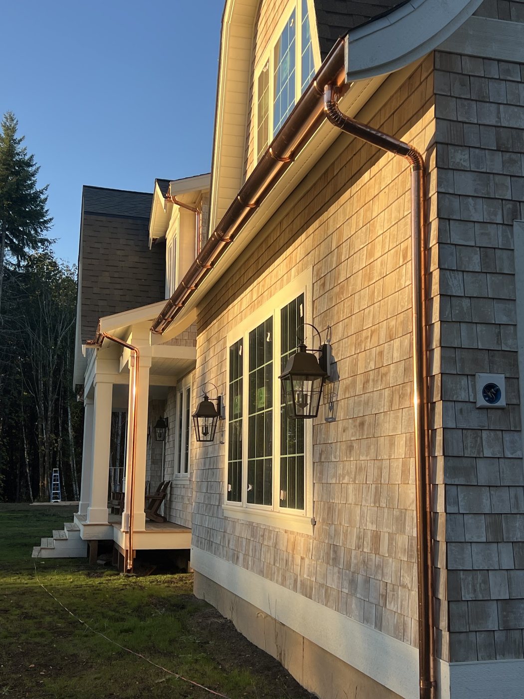 Hand-fitted copper gutters and downspouts catching the evening light